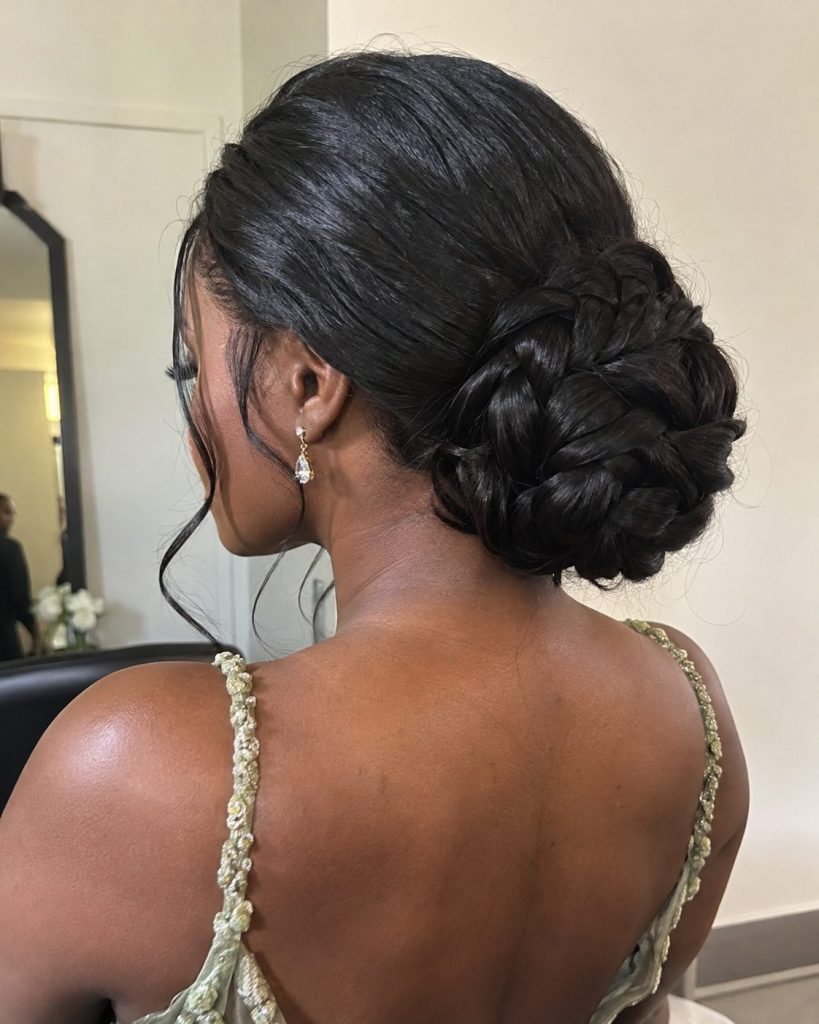 A low braided bun made from glossy black hair photographed from behind in a salon