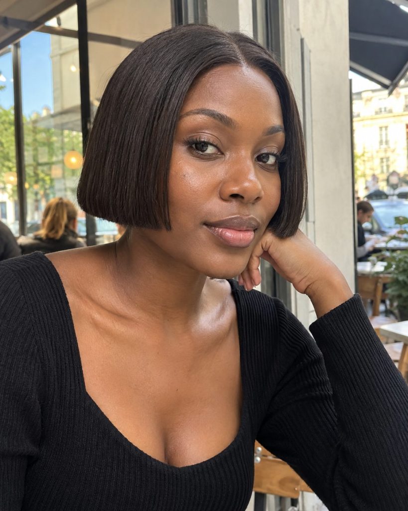 Short straight dark-brown mini bob with a neat jawline cut at a street cafe