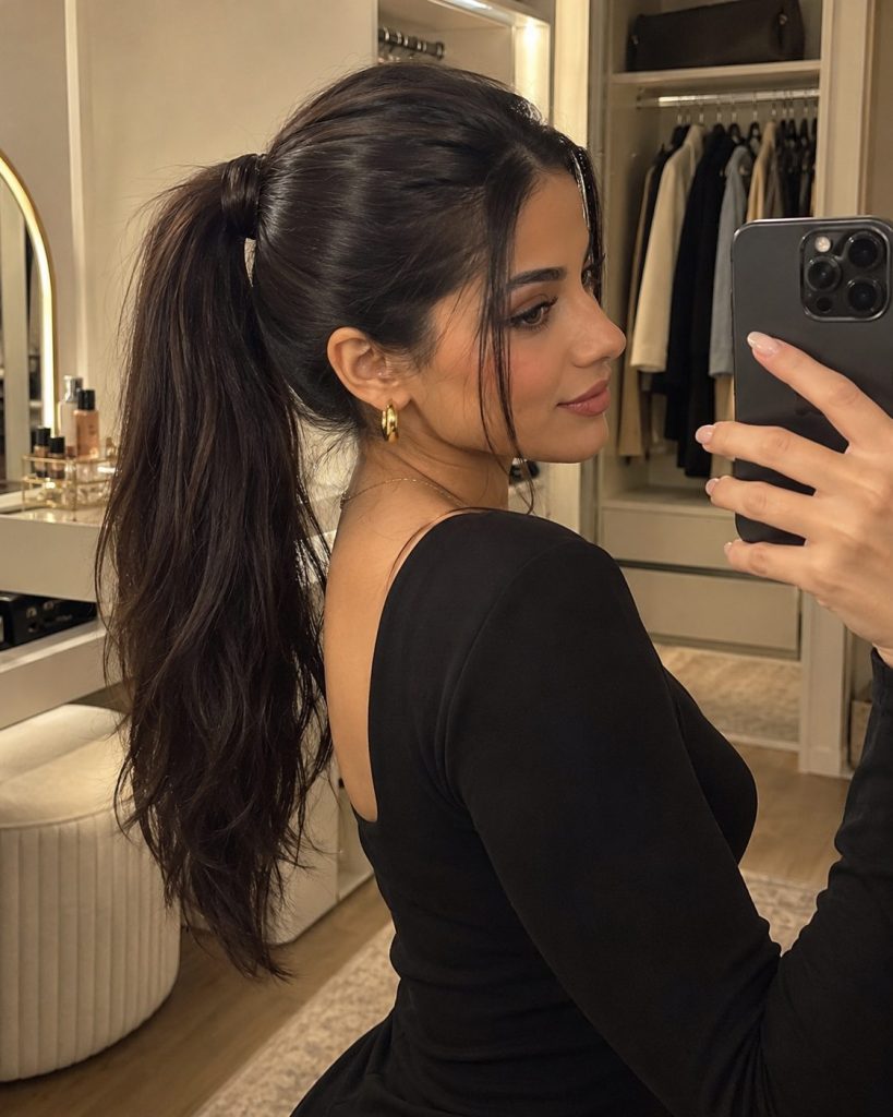 Long dark high ponytail with a strand of hair wrapped around the base in a dressing room mirror photo
